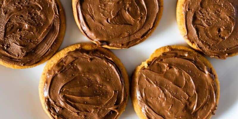 four cookies with chocolate frosting on a white plate